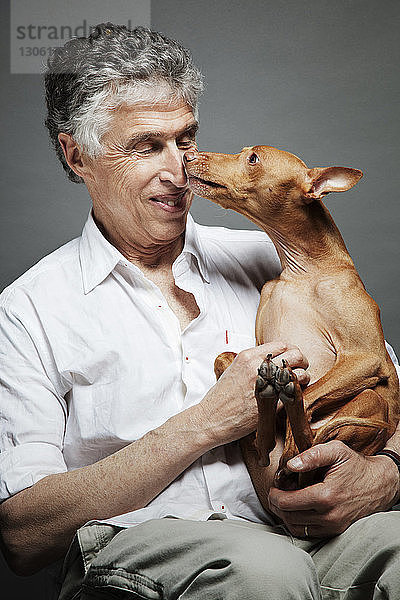 Mann mit Hund vor grauem Hintergrund sitzend