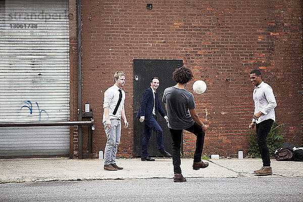 Glückliche Freunde spielen Fussball auf der Strasse