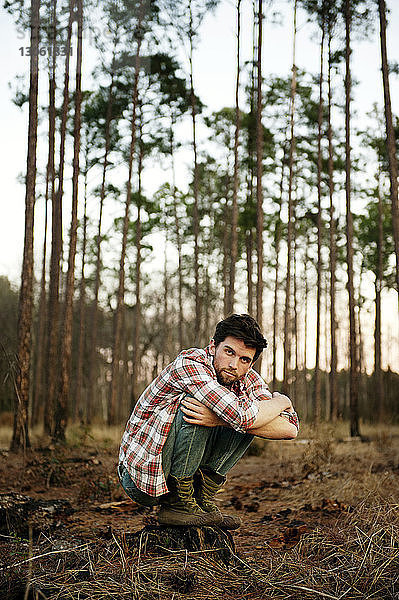 Porträt eines auf einem Feld im Wald kauernden Mannes