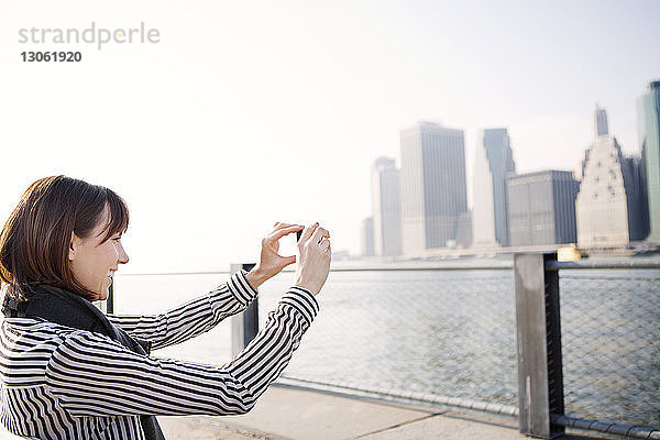 Glückliche Frau fotografiert Stadtlandschaft am East River