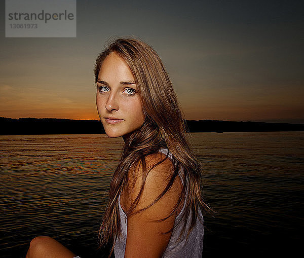 Porträt einer schönen Frau am Seeufer gegen den Himmel bei Sonnenuntergang