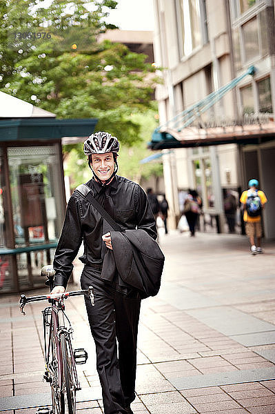 Porträt eines Geschäftsmannes zu Fuß mit Fahrrad auf der Straße