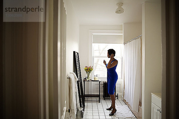 Seitenansicht einer Frau  die am Spiegel steht und sich zu Hause anzieht