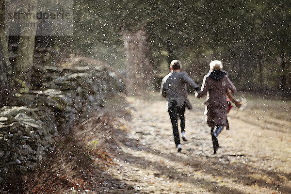 Rückansicht eines Paares  das im Winter auf dem Feld läuft