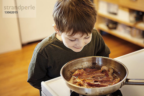 Neugieriger Junge schaut sich zu Hause Essen auf dem Herd an