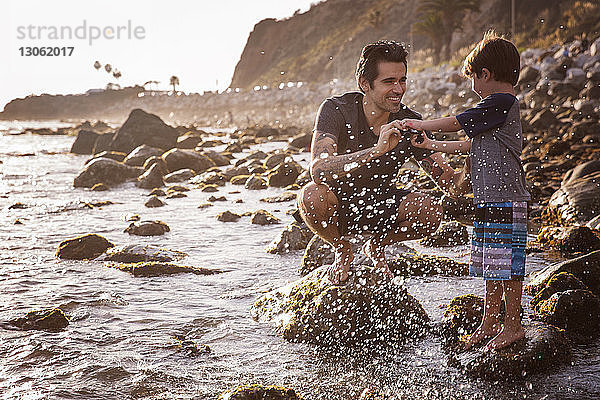 Glücklicher Vater und Sohn genießen am Strand bei Sonnenuntergang