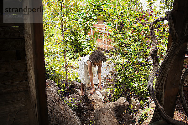 Hochwinkelansicht eines Mädchens  das auf einen Baumstamm klettert  vom Baumhaus aus gesehen