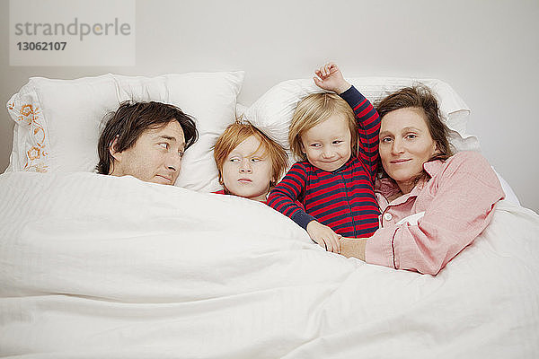 Glückliche Familie liegt zu Hause auf dem Bett