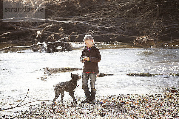 Junge steht mit Hund am Fluss
