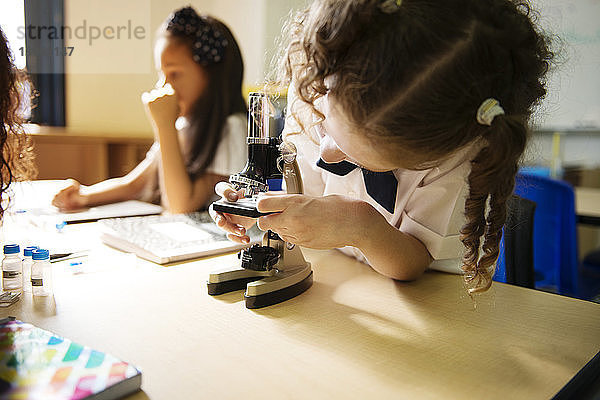 Mädchen mit Mikroskop am Tisch im Labor