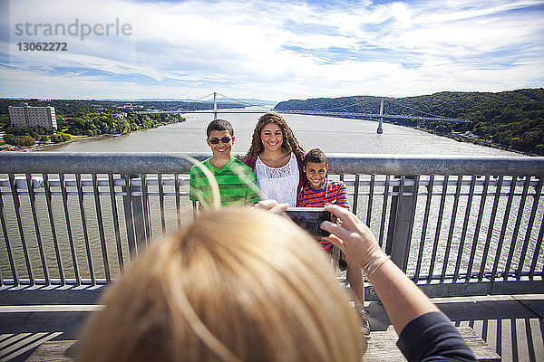 Beschnittenes Bild einer Frau  die Geschwister fotografiert  die gegen den Himmel stehen