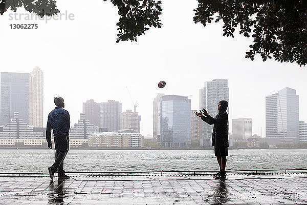 Freunde spielen mit Fussball auf der Promenade gegen das Meer