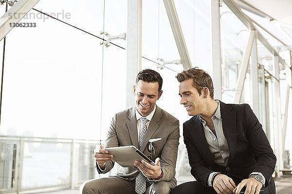 Glückliche Geschäftsleute mit Tablet-Computer auf der Bank sitzend