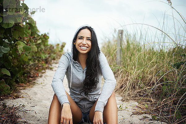 Porträt einer glücklichen Frau am Strand sitzend