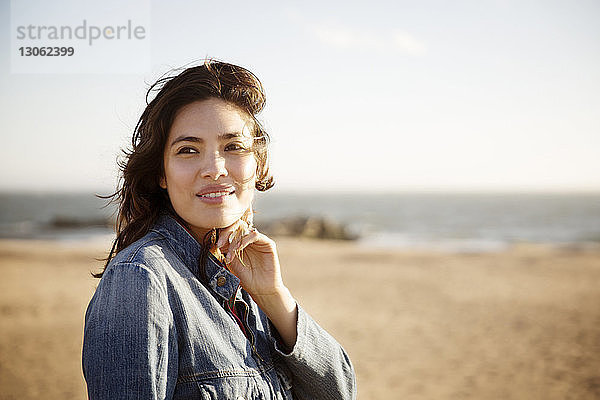 Frau lächelt  während sie am Strand steht