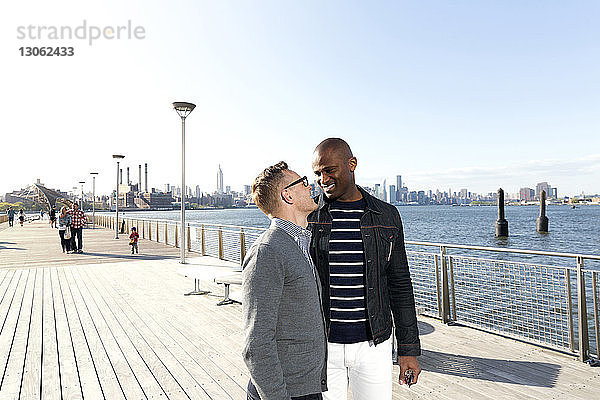Glücklicher Mann schaut seinen Freund an  während er am Pier vor klarem Himmel steht