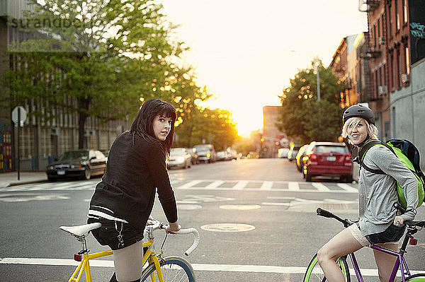 Porträt von Freunden mit Fahrrädern auf der Stadtstraße bei Sonnenuntergang