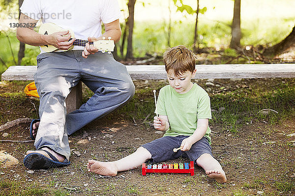 Vater und Sohn spielen mit musikalischen Spielzeuginstrumenten auf dem Spielplatz