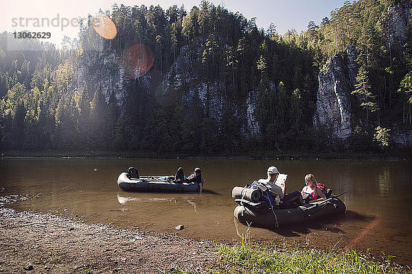 Freunde sitzen im Floß auf dem Fluss vor Felsformationen