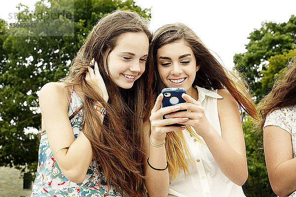 Freundinnen lächeln beim Blick auf das Mobiltelefon