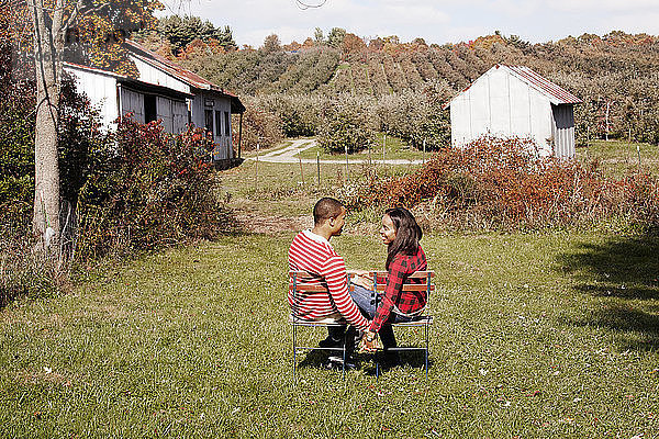 Paar  das sich an den Händen hält und einander anschaut  während es im Hinterhof sitzt