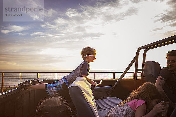 Familie im Pickup am Meer bei Sonnenuntergang