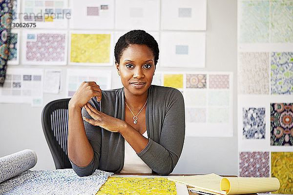 Porträt einer Modedesignerin  die in einem Workshop am Schreibtisch sitzt