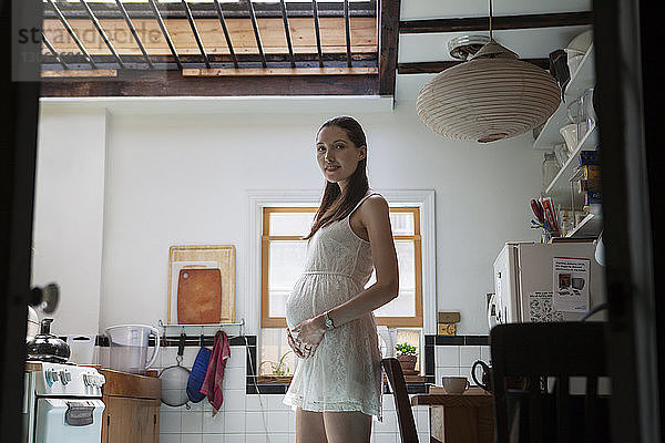 Porträt einer schwangeren Frau in der Küche stehend