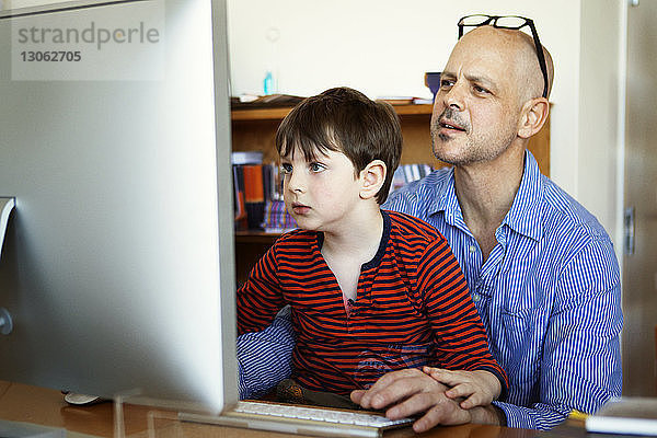 Vater und Sohn nutzen Desktop-Computer zu Hause