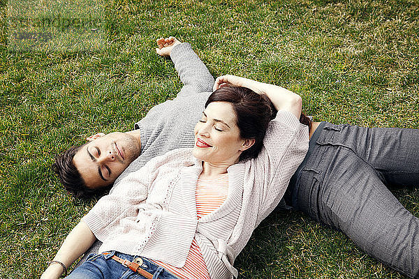 Hochwinkelaufnahme eines glücklichen Paares  das im Park auf dem Rasen liegt