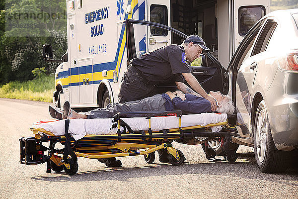 Rettungshelfer legt Patient im Auto auf Krankenhausbahre