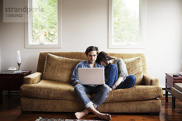 Mann benutzt Laptop-Computer  während seine Freundin zu Hause auf der Schulter liegt
