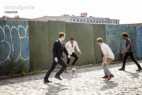 Männer spielen Fussball an der Wand auf der Strasse
