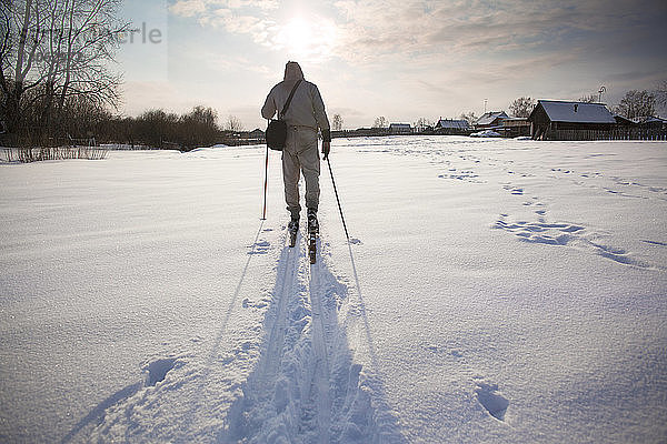 Rückansicht eines Mannes beim Skifahren auf schneebedecktem Feld