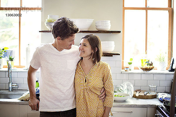 Glückliches Paar schaut sich an  während es in der Küche steht