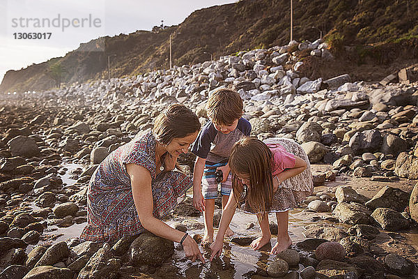Glückliche Familie taucht am Strand den Finger ins Wasser