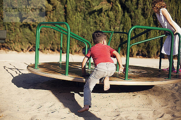 Geschwister spielen auf dem Karussell im Park