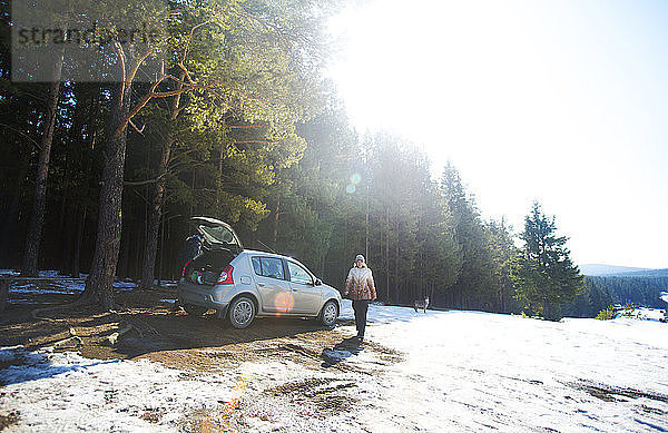 Freunde mit dem Auto im Wald an einem sonnigen Wintertag