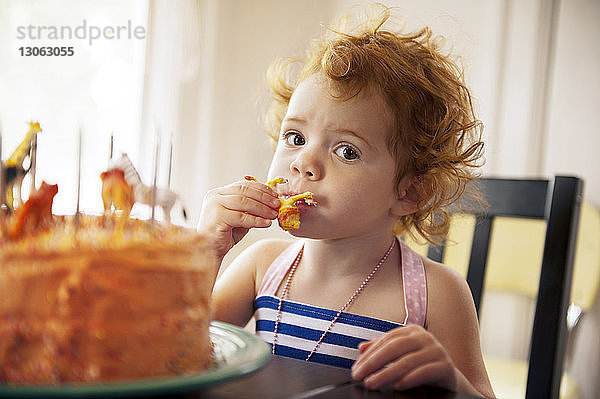 Porträt eines am Tisch sitzenden Mädchens beim Kuchenessen