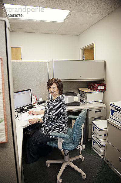 Glückliche reife Frau arbeitet am Schreibtisch im Büro