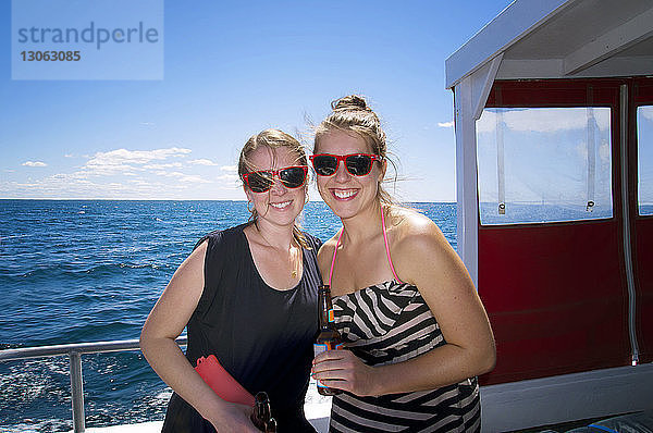 Porträt von glücklichen Freundinnen  die in einem Boot stehen  das auf dem Meer segelt
