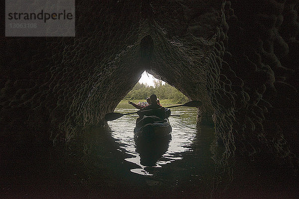 Freunde reisen im Boot auf dem Fluss bei der Höhle