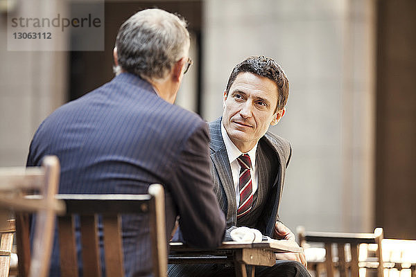 Geschäftsleute diskutieren  während sie im Straßencafé sitzen