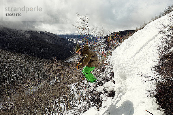 Seitenansicht eines Skifahrers  der auf einem schneebedeckten Berg springt