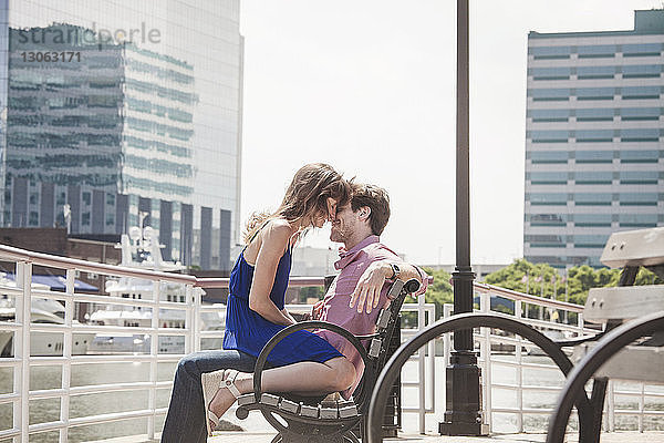 Romantisches Paar auf Bank am Fluss sitzend