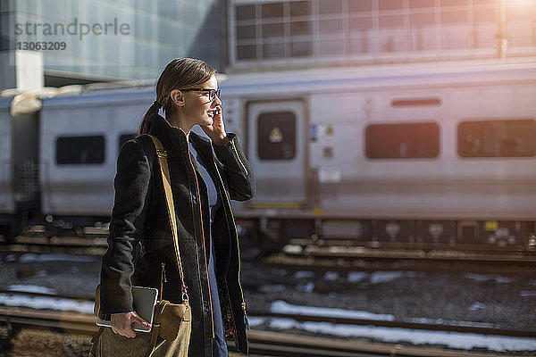 Frau telefoniert beim Gehen am Bahnhof