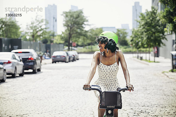 Lächelnde Frau mit dem Fahrrad auf der Straße in der Stadt