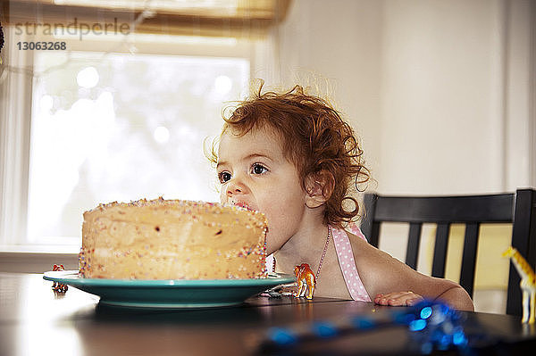 Mädchen isst Kuchen  während sie zu Hause am Tisch sitzt