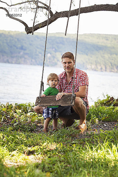 Porträt von Vater und Sohn bei der Seilschaukel am Seeufer