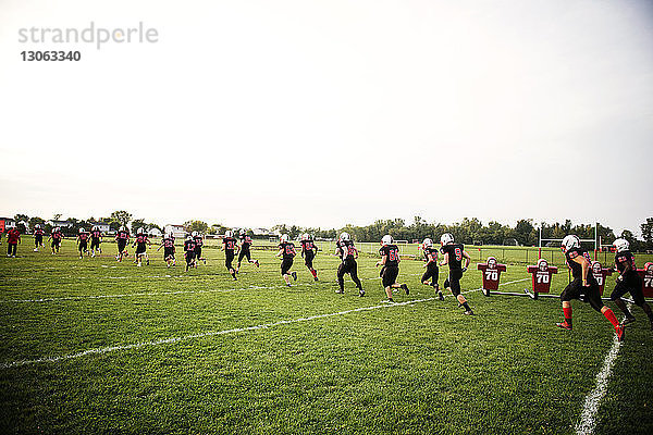 American-Football-Team rennt auf Rasen gegen den Himmel